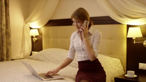 Vrouw is praten over de telefoon en doen van smth in haar laptop — Stockvideo