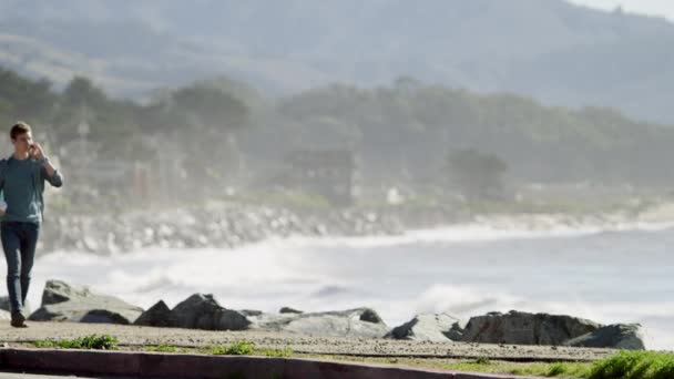 Joven caminando a lo largo de la costa del océano Pacífico — Vídeo de stock