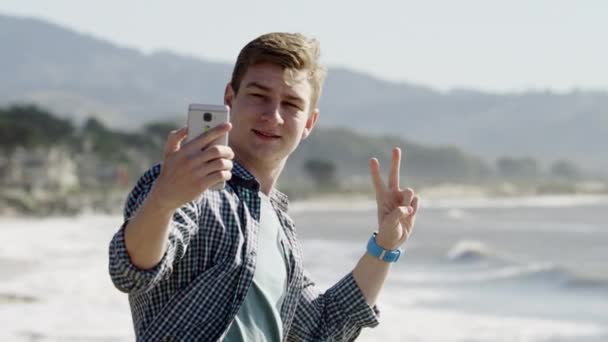 Молодой человек стоит у побережья Тихого океана — стоковое видео