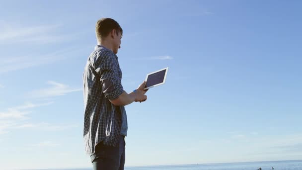 Mladý pohledný používá digitální tablet na pobřeží — Stock video