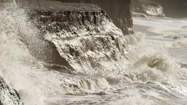海の波がビーチと岩の崖に衝突します。 — ストック動画