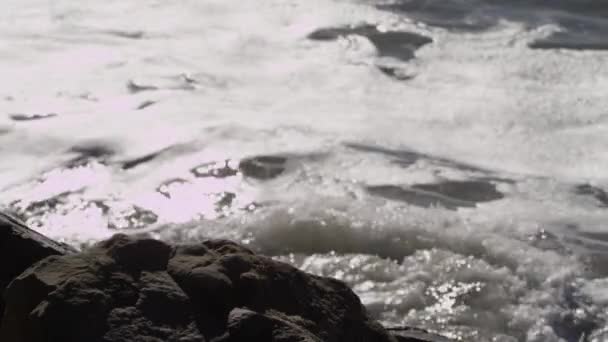 Ondas oceânicas colidem com uma praia e penhascos rochosos — Vídeo de Stock