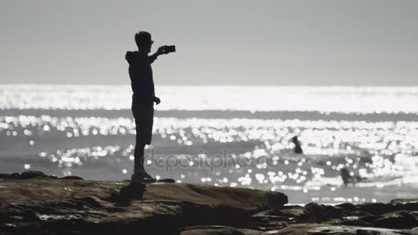 L'homme au bord de la mer prend une photo d'un paysage merveilleux — Video