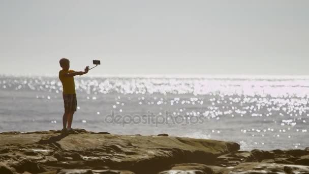 Маленький мальчик делает самоснимок на пляже — стоковое видео