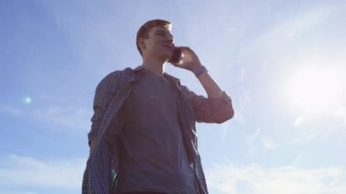 Güzel genç adam onun smartphone bir sokakta üzerinde neşeli sohbet ediyor