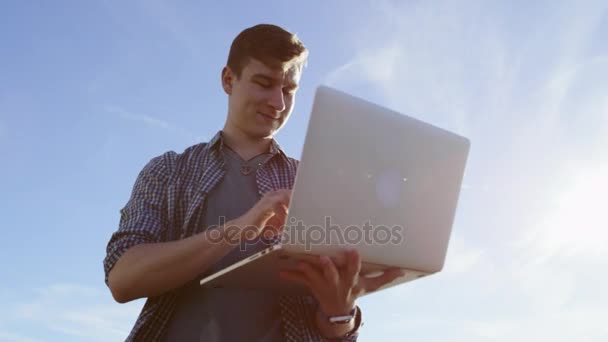 Young beautiful man with a laptop on a coast — Stock Video