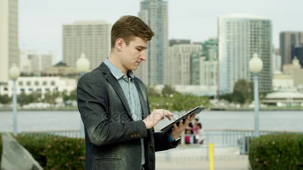 Jeune beau avec une tablette PC sur une rue — Video