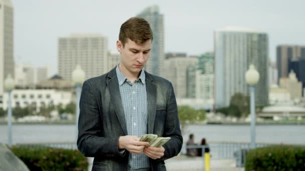 Un jeune homme d'affaires compte son argent dans une rue de Coronado, San Diego — Video