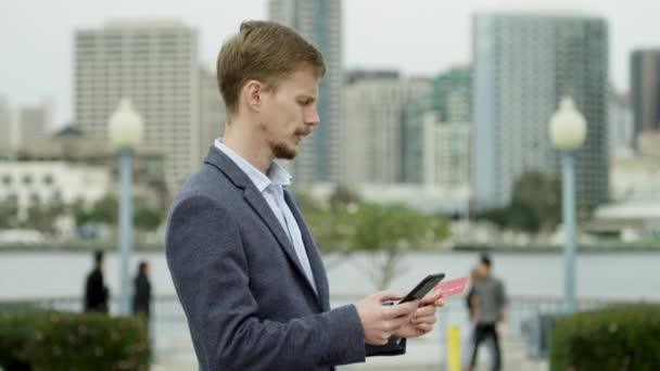 Mladý vousatý chlap něco kupuje přes Internet na ulici Coronado, San Diego — Stock video