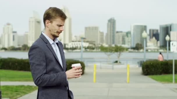 Молодой бородатый человек с чашкой чая ждет кого-то — стоковое видео