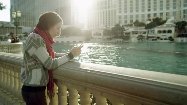 Donna è in piedi di fronte fontana a e sms — Video Stock