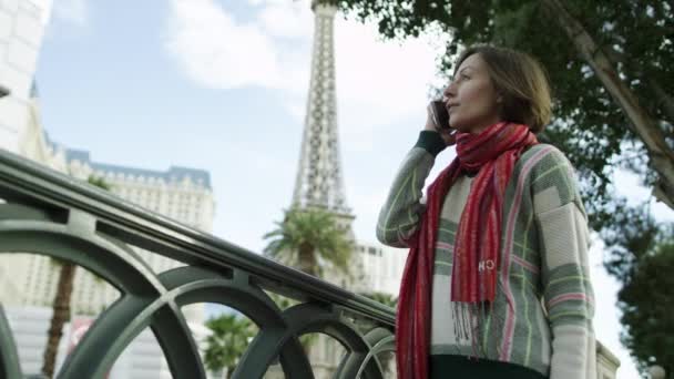 Jeune femme magnifique parle sur un smartphone avec la tour Eiffel sur un fond — Video