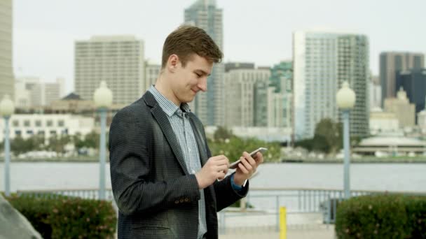 Uomo d'affari sta inviando un messaggio di testo mentre in piedi su una strada a Coronado — Video Stock