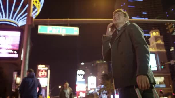 Jonge knappe toeristische is praten over zijn smartphone tijdens het wandelen in de verlichte straat in Las Vegas — Stockvideo