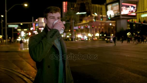 Jovem está bebendo chá em uma rua noturna em Vegas — Vídeo de Stock
