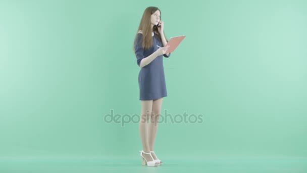 En flicka pratar i telefon med Urklipp i händerna — Stockvideo