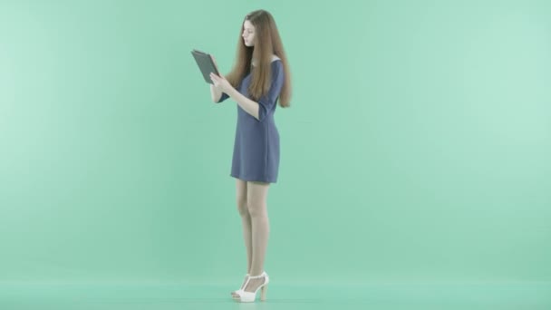 A smiling girl stands holding a tablet in hands — Stock Video