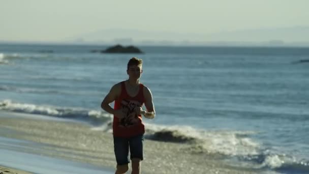 Atleta bonito está fazendo um treino em uma praia — Vídeo de Stock