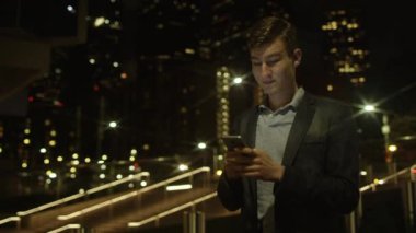 Yakışıklı genç işadamı duran bir sokakta iletişim için onun smartphone kullanarak