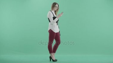 elinde telefon ile genç bir kadın duruyor