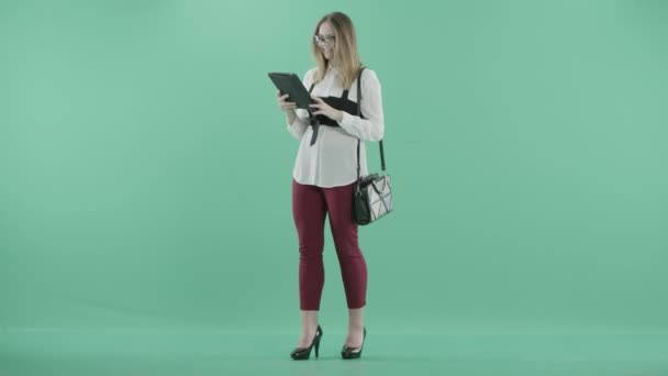 A young woman stands using a tablet — Stock Video