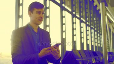 Genç adam havaalanında cep telefonunu üzerinde konuşuyor