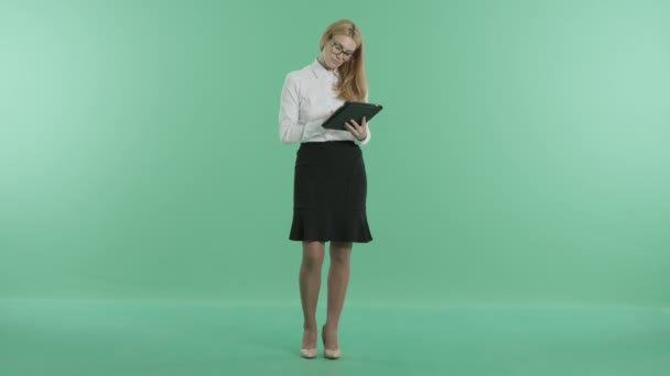 Uma menina inteligente fica segurando um tablet nas mãos — Vídeo de Stock