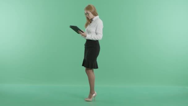 Бізнес-леді в окулярах стоїть за допомогою планшета — стокове відео