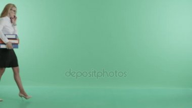 bir iş kadını kağıtları taşıyan telefonda konuşuyor