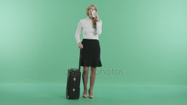 A sleepy woman drinks coffee standing with her baggage — Stock Video