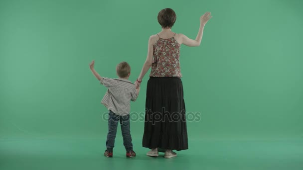 Mother and her little son stand backs to the viwer and wave hands — Stock Video