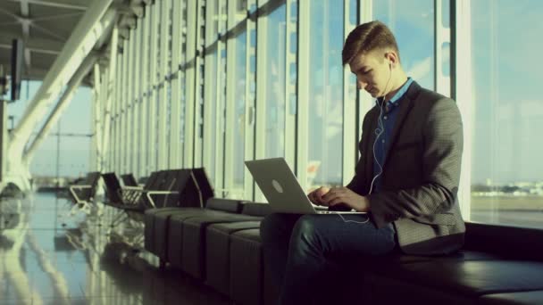 Joven escritor con un portátil en el aeropuerto de Londres — Vídeo de stock