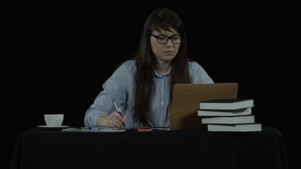 Дівчина на чорному тлі робить нотатки — стокове відео