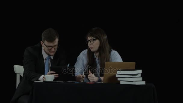Deux étudiants assis au bureau discutent de ce qui est écrit sur un écran de table plane — Video