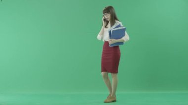 Çekici kadın elinde klasörlerle yürür ve telefon aramayý cevaplar
