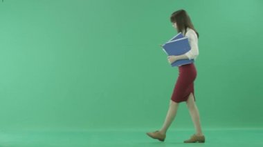 Resmi giysili güzel kızı holding klasörleri yürür ve bir aramaya cevap vermek için durur