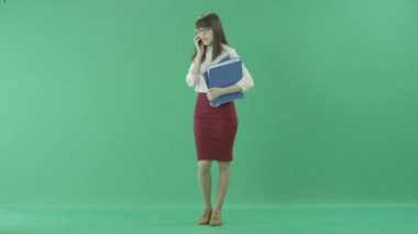 Güzel iş kadını iki klasör elinde tutan gülümser ve onun cep telefonu konuşuyor