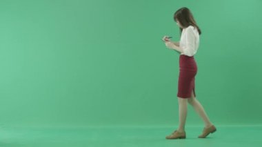 Genç iş kadını bir cep telefonunuzun konuşma ve notlar bir pano ile yürüyor