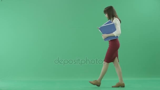 Vacker flicka i formella kläder går anläggningen mappar och stannar för att besvara ett samtal — Stockvideo