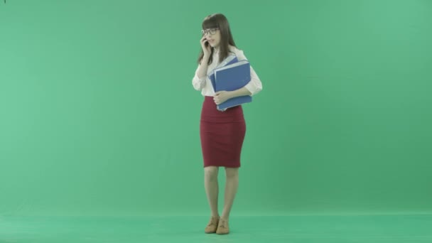 Krásný obchodní žena mluví o její mobil a usmívá se v ruce drží dvě složky — Stock video