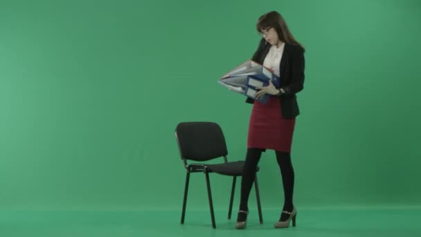 Giovane donna d'affari che guarda attraverso i documenti in una cartella mentre parla sul cellulare — Video Stock