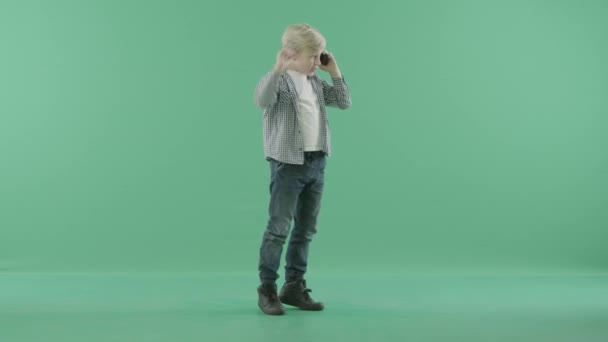 Chlapec hovoří s agitace na mobil před zeleným pozadím — Stock video