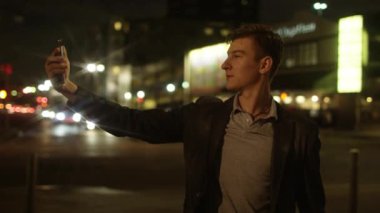 Genç erkek bir sokakta kendini bir kaç fotoğrafını çekmek