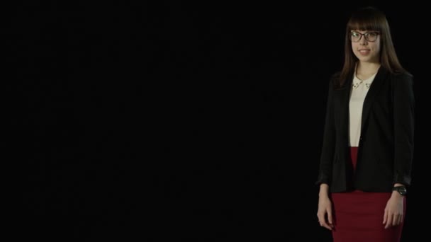 Attraktiva flicka står på en svart skärm och visar objekt — Stockvideo