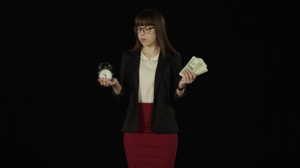 Pretty young woman holds her hands up as scales with a clock and money in it — Stock Video