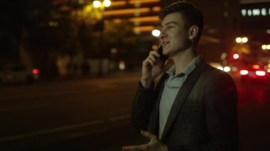 Genç yakışıklı adam konuşmak bir telefon sahip ve bir taksi yakalamak için