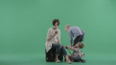 İki çocuk iskambil çevrede onların annesi onun smartphone dalmış.