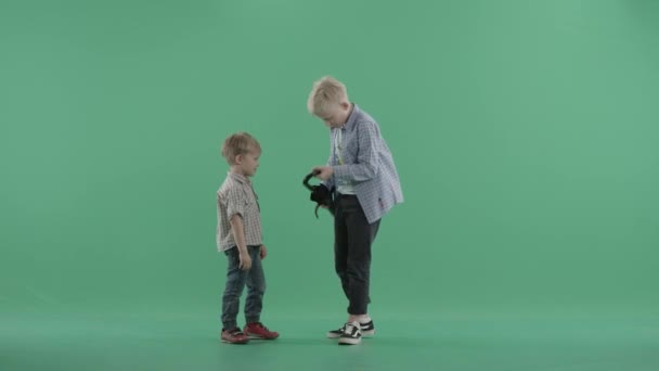 Older brother opens an umbrella in front of his younger sibling — Stock Video