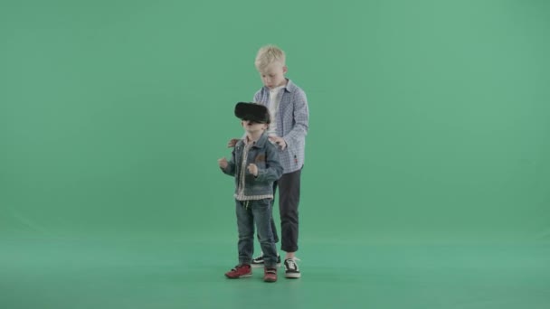 Small boy stands in vr glasses with his older brother — Stock Video