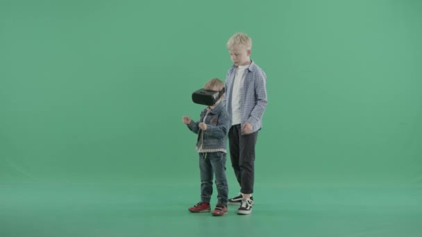 Small boy wears vr glasses while his older brother holds him in his arms — Stock Video